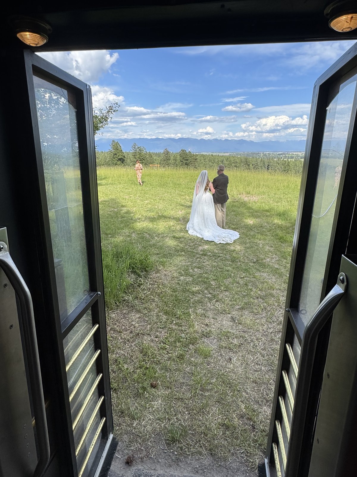 View down the trolley aisle toward a couple in a green field