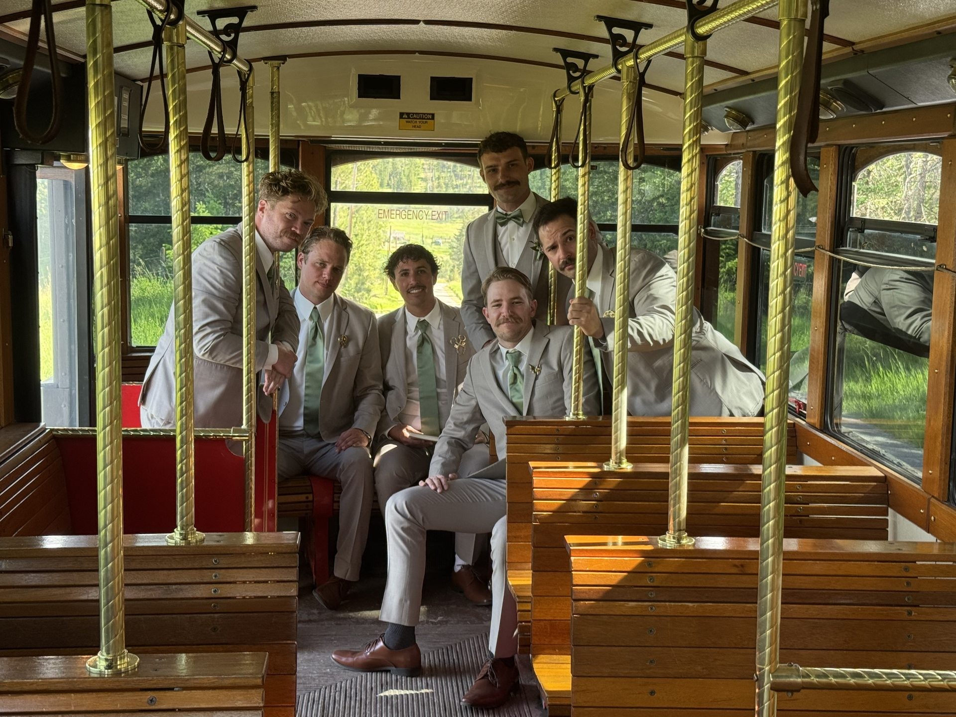 Groomsmen riding inside a Montana trolley with oak seats and brass rails