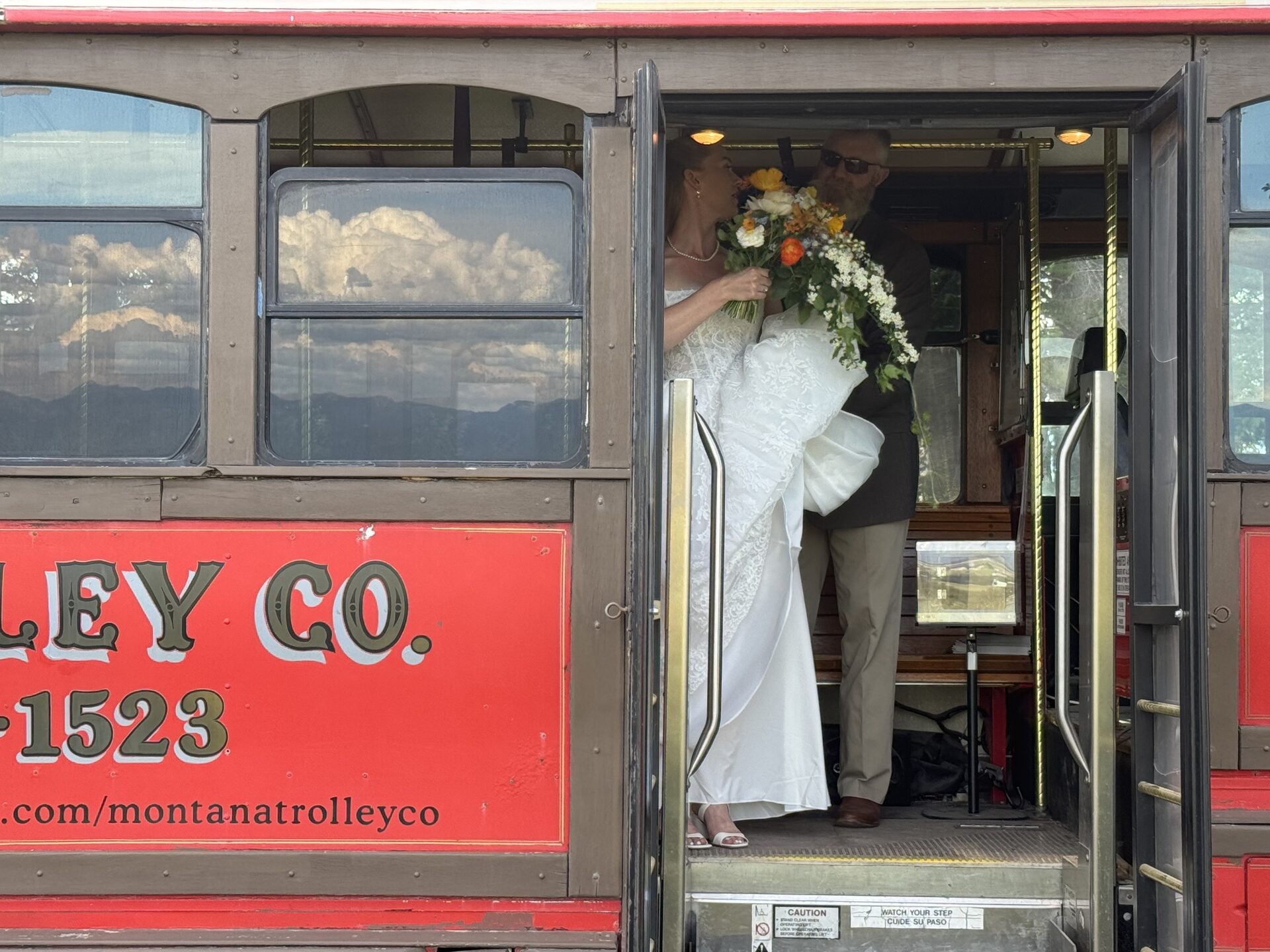 Bride and groom stepping off a Montana trolley with bouquet in hand